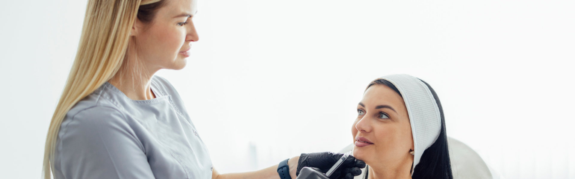 Specialist administering a cosmetic treatment to a woman.
