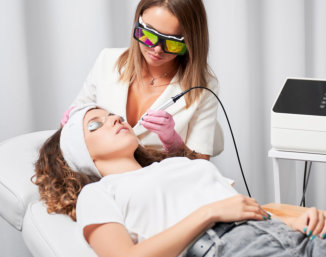 Aesthetician performing a laser skin treatment on a patient.