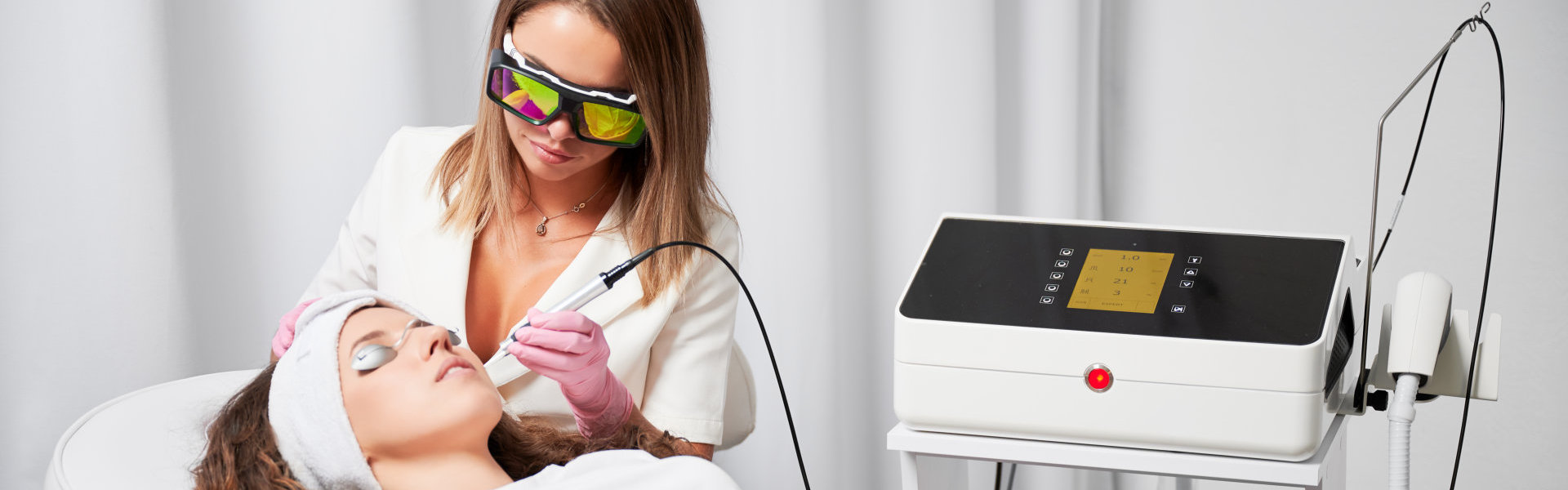 Aesthetician performing a laser skin treatment on a patient.